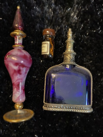 Trois fioles ornées remplies de potions secretes sur un fond de fumée et de poussière