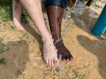 Quelqu’un verse de l’eau sur les pieds d’un homme noir et d’un homme blanc. Pas de discrimination.